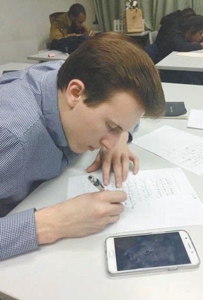 外国学生马修·塞申斯在课堂上认真地用<a href='/Gaokao/Professional/Details/570209'>中文</a>完成老师布置的作业。