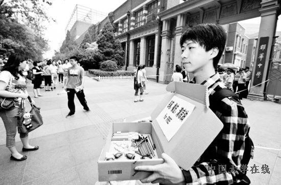 上午，在天津耀华中学考点外，一名不参加高考的同学手捧免费的铅笔、橡皮和清凉油供考生取用。