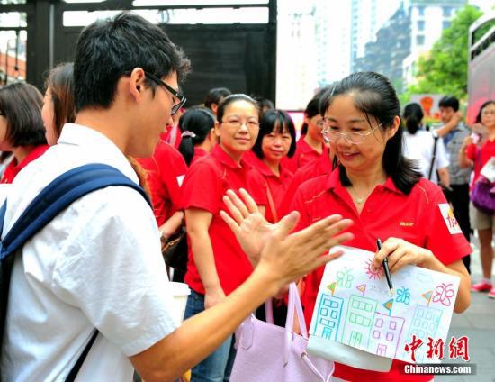 老师们统一穿着红色上衣,高举标语为考生加油(资料图)。中新社发 陈骥旻 摄